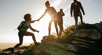 Group of people hiking with one woman giving a hand to another